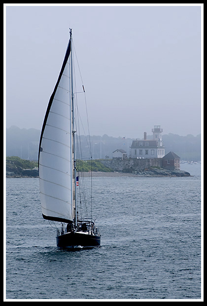 sailboat passes Rose Island light in the fog