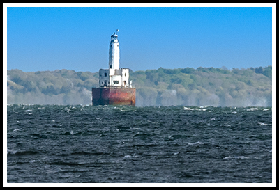 fishing boat passes by Cleveland Zledge light view from a distance